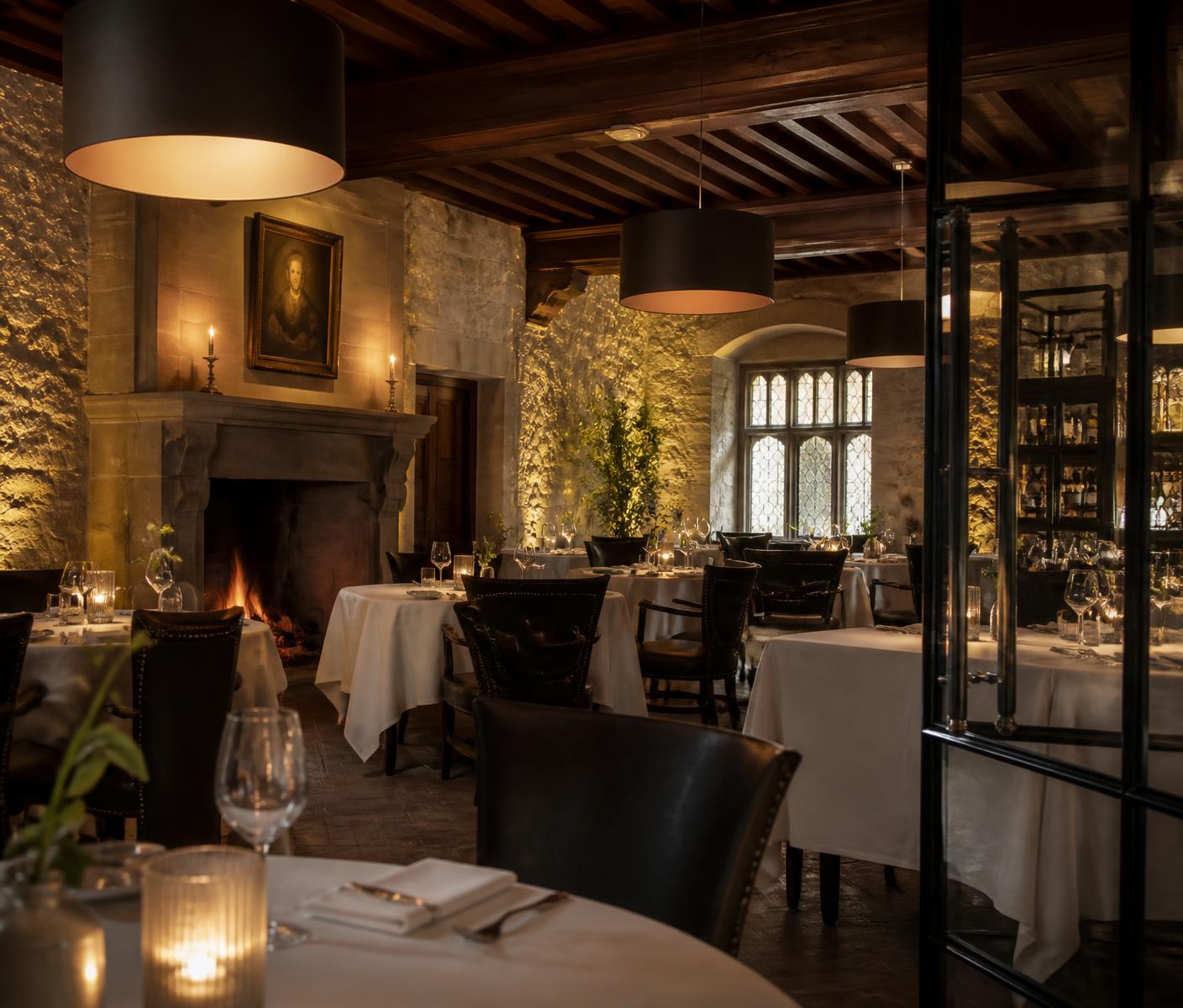 Salão interno do restaurante com paredes de pedra e mesas à luz de velas